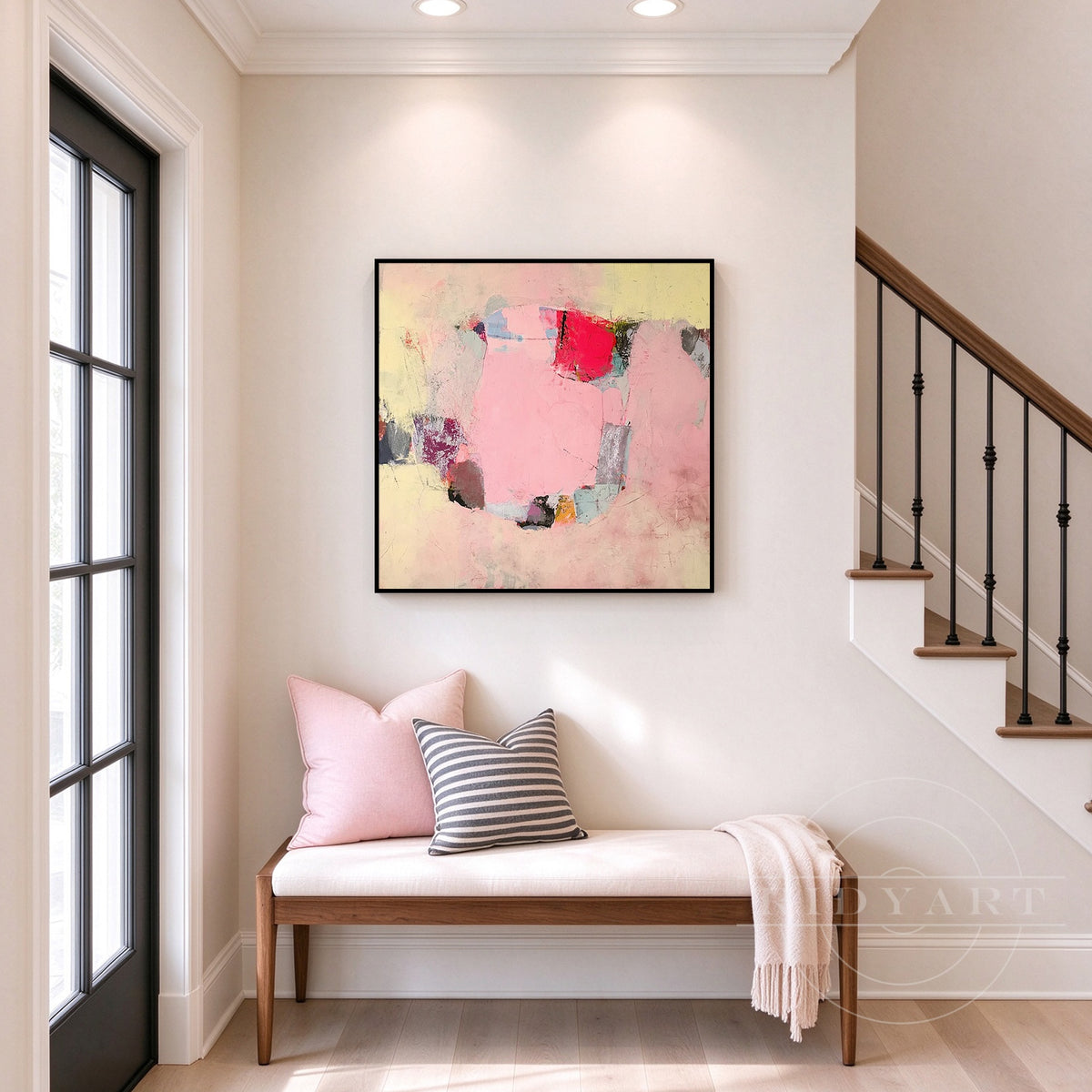 Framed pink and yellow color block canvas art displayed on a neutral living room feature wall with warm lighting.