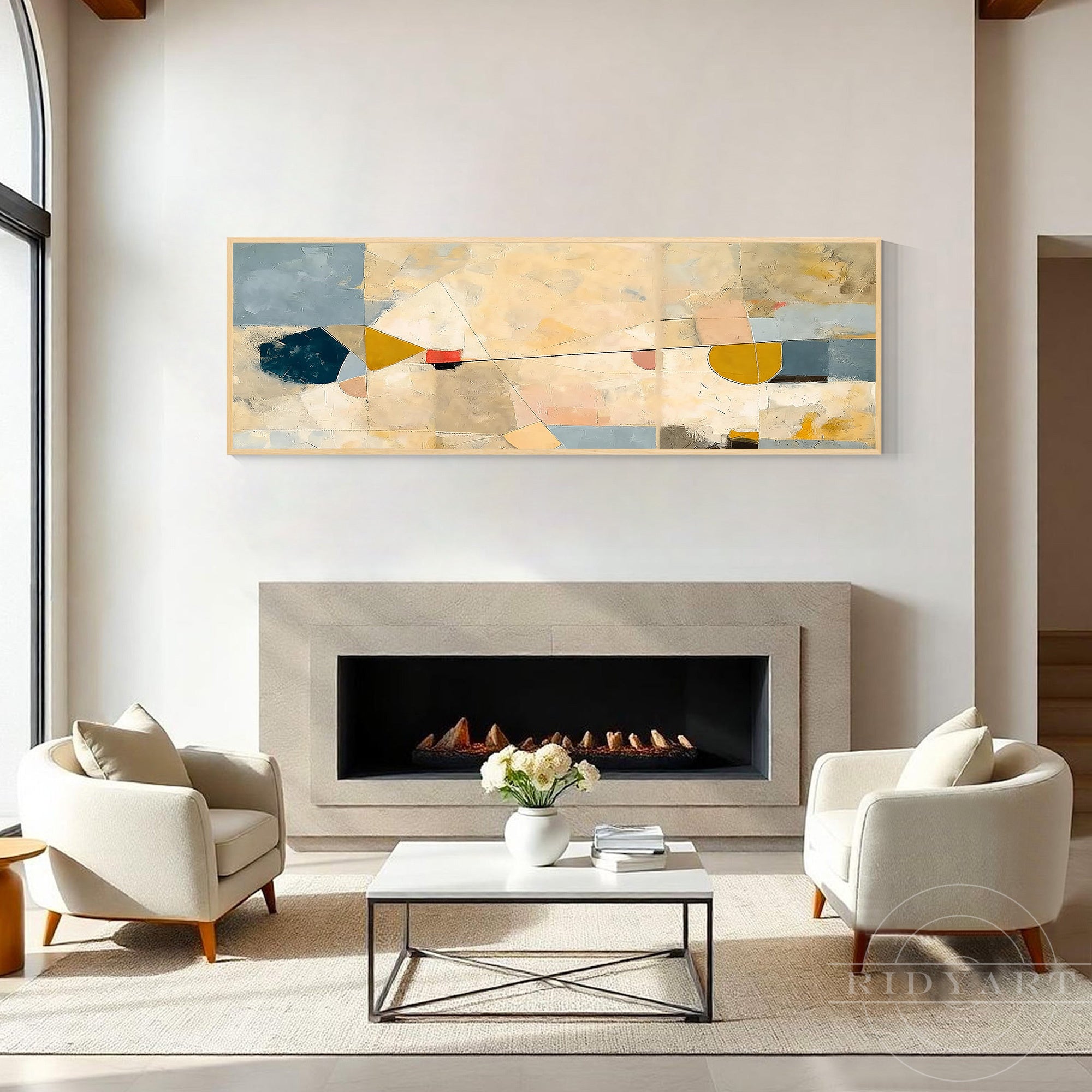 Panoramic horizontal abstract artwork hanging over a modern stone fireplace flanked by ivory armchair seats.