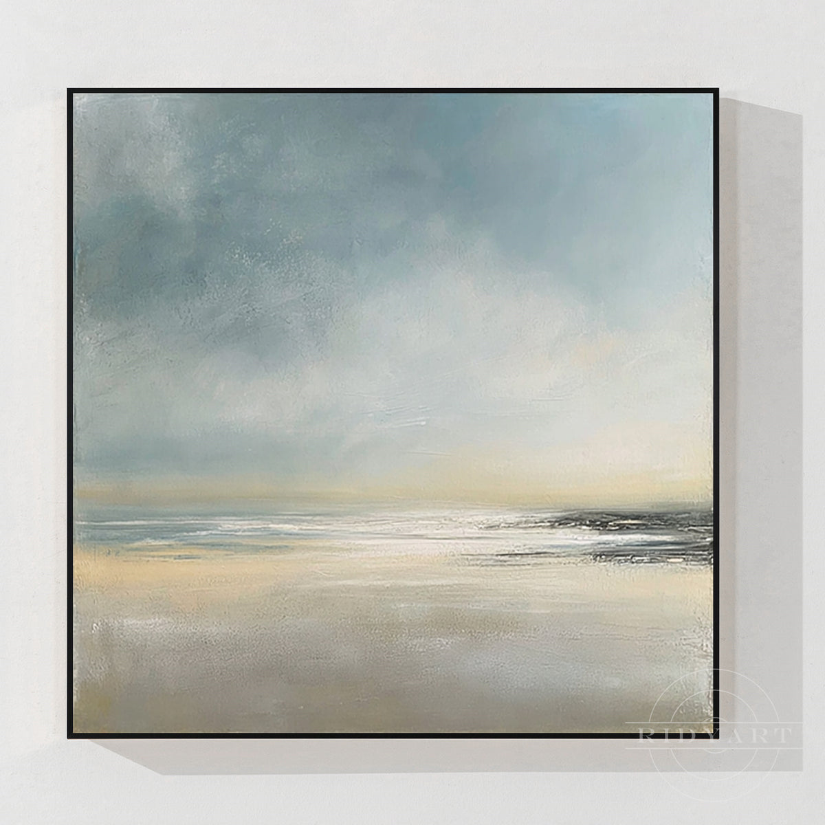 Square abstract coastal seascape painting featuring hazy blue clouds, soft golden beach tones, and sea horizon in a slim black floating frame.