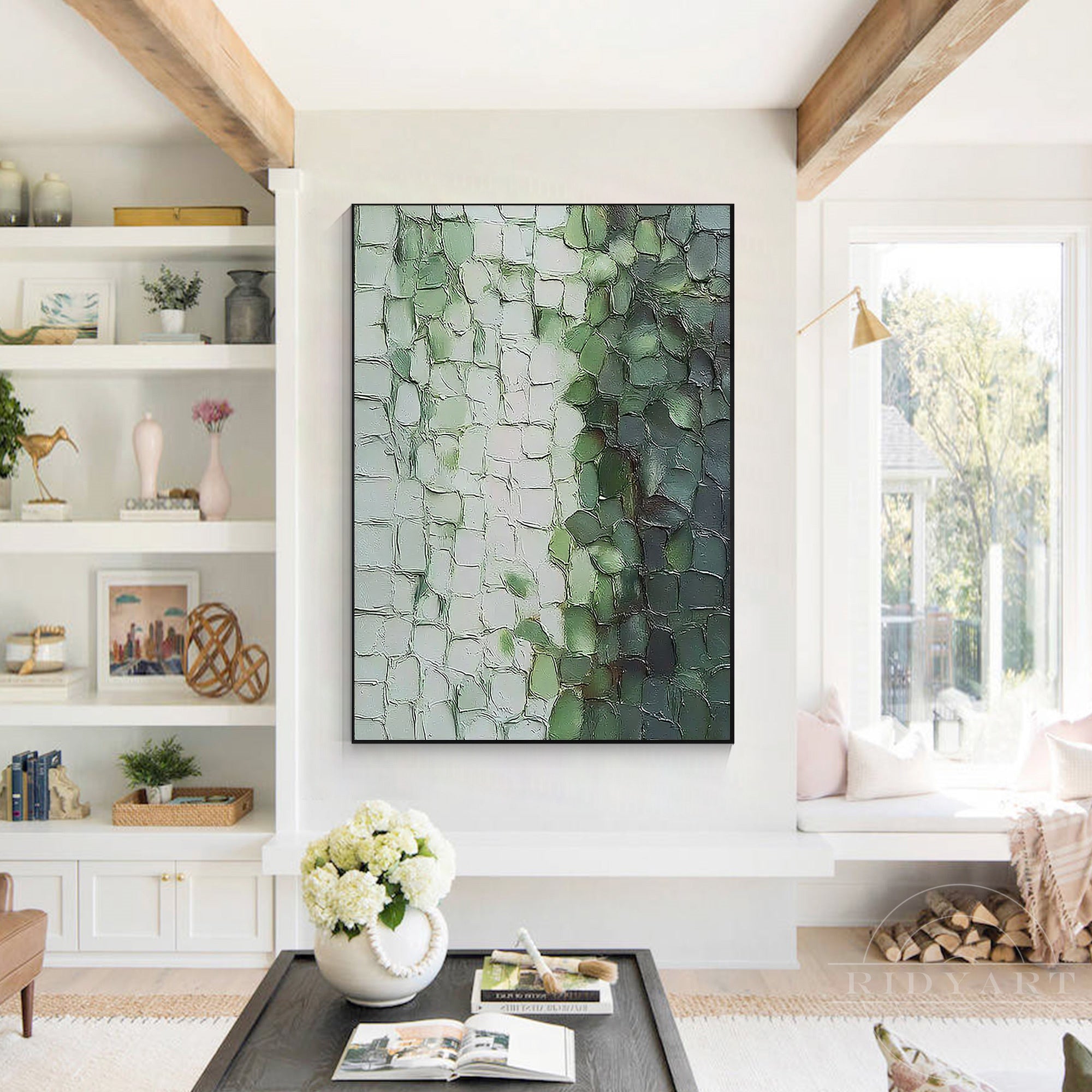 Vertical sage green heavy textured canvas art hanging on a white wall above a low black coffee table in a modern organic living room.