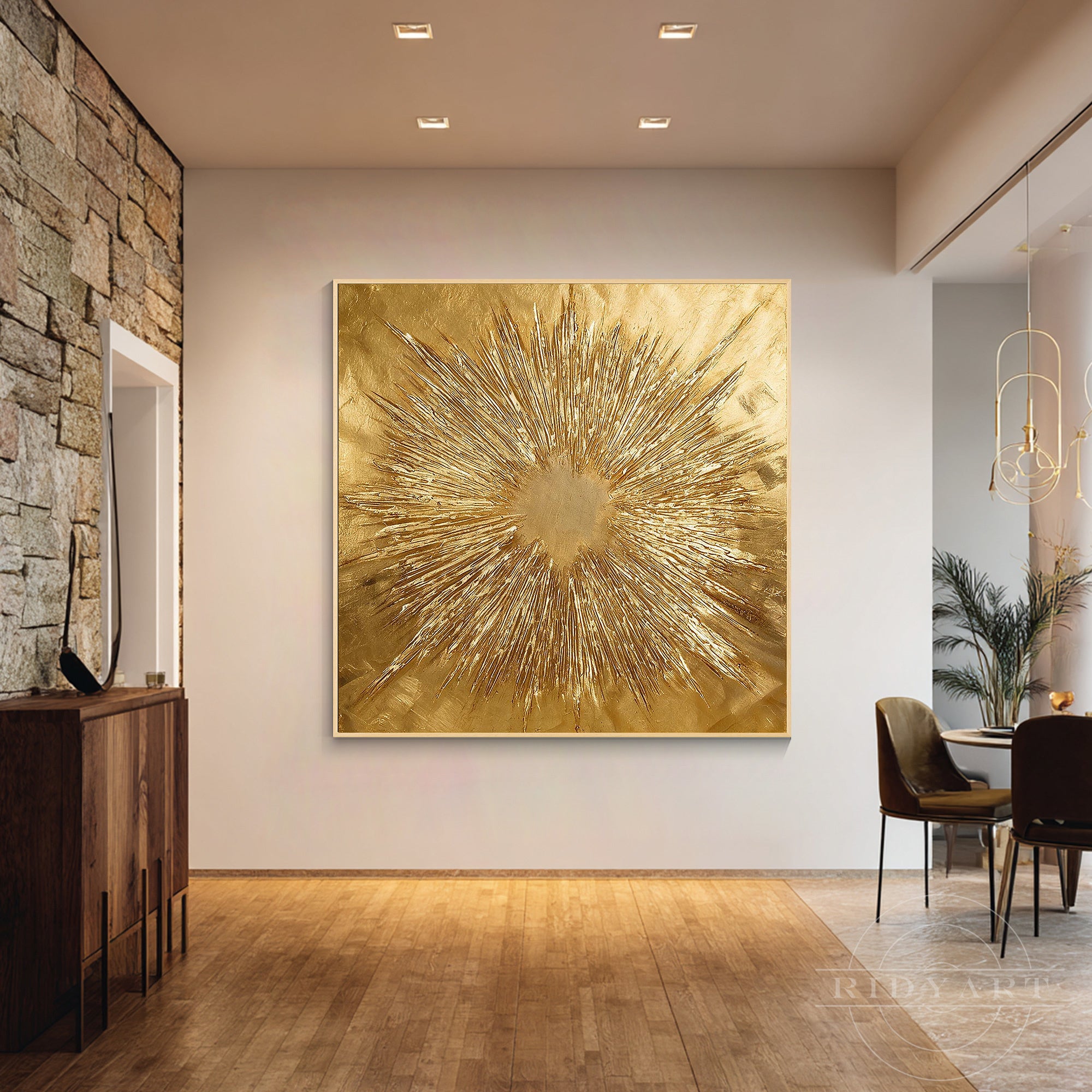 Oversized textured gold starburst canvas art mounted on a plain wall at the end of a hallway next to a dining area with dark chairs.