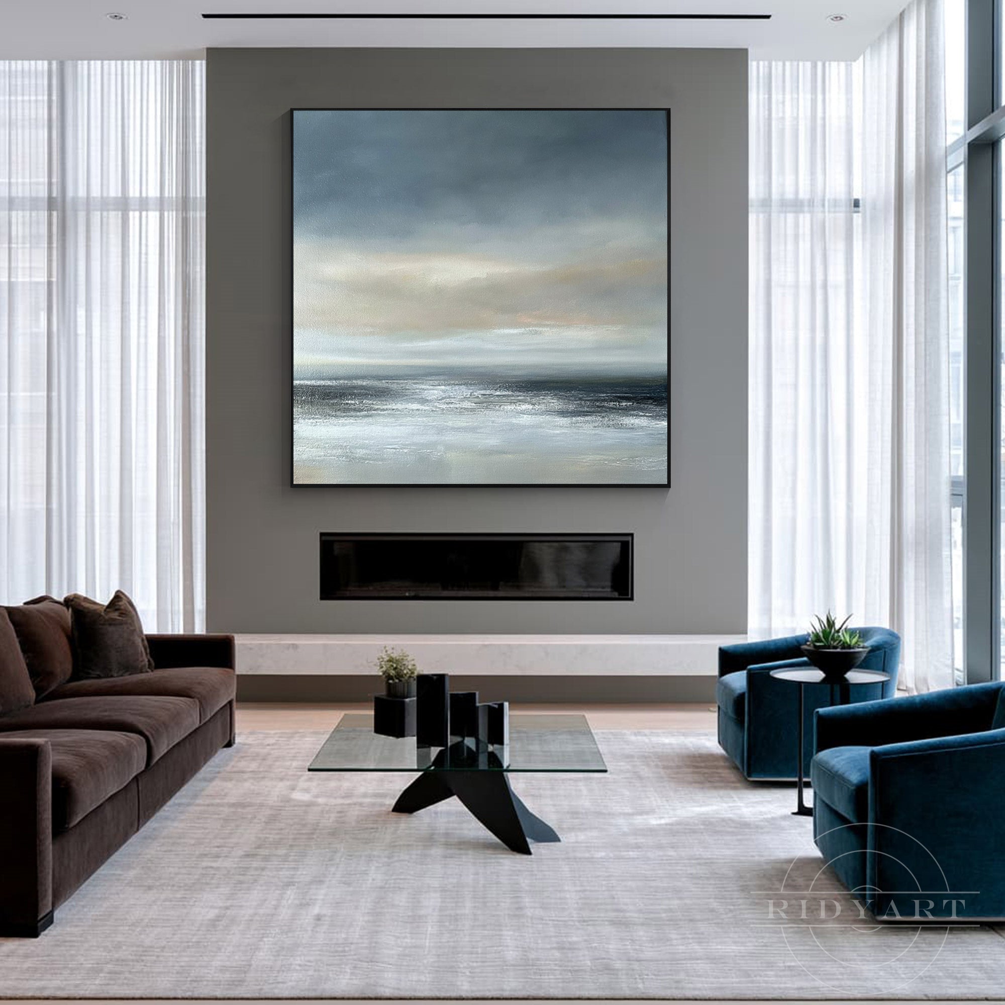 Oversized square coastal horizon wall art mounted over a modern dark grey fireplace in a contemporary living room.