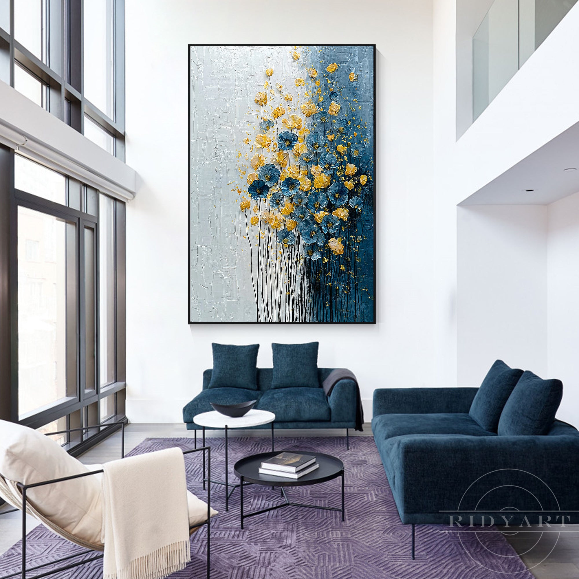 Vertical abstract floral canvas artwork hanging above a deep blue sofa and navy area rug in a double-height high-ceiling living room.