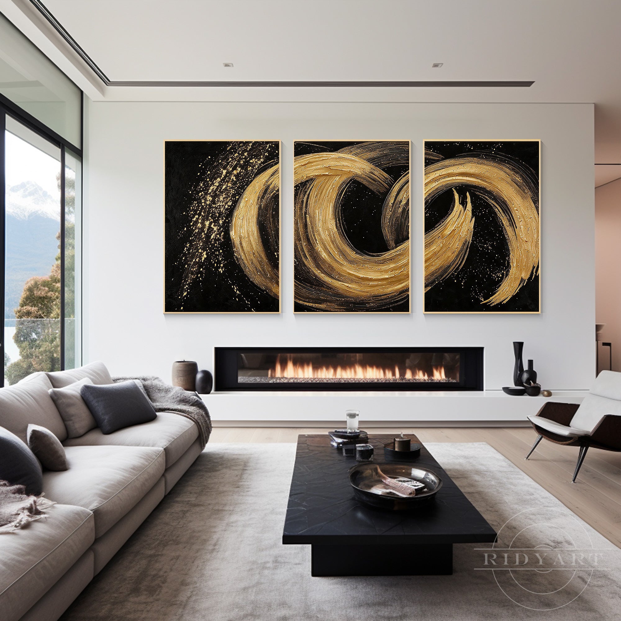 Black and gold abstract 3-piece canvas painting set mounted above a modern horizontal fireplace in a bright living room with white sofas.