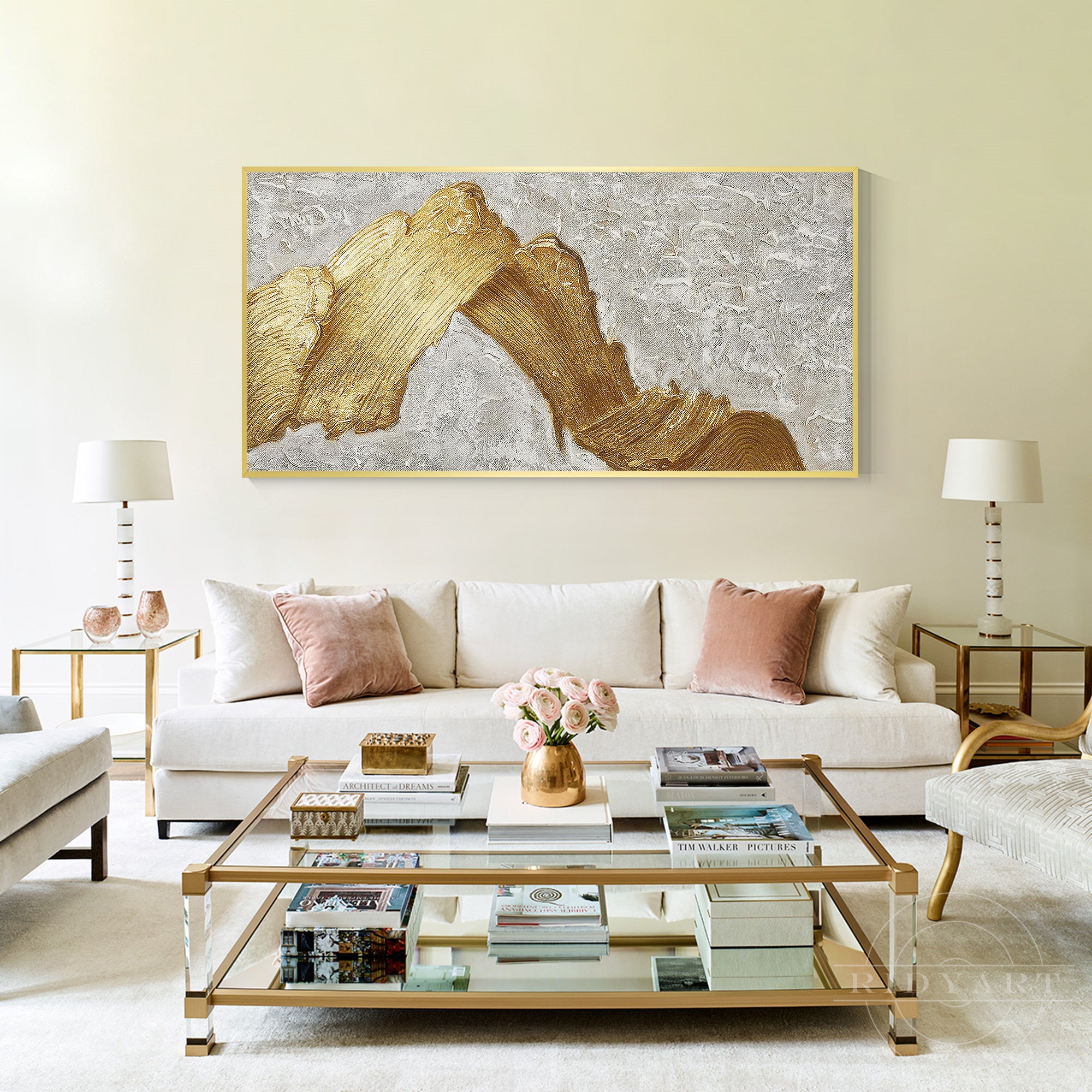 Large horizontal white and gold mountain abstract canvas painting hanging above a beige sofa in an elegant cream living room.