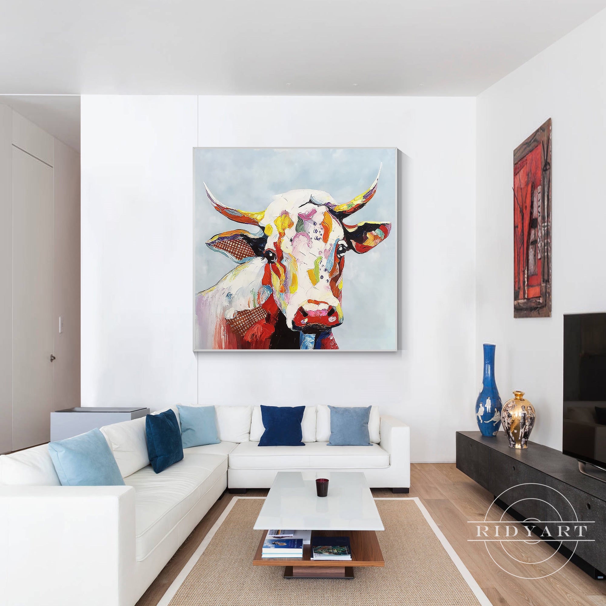 Large abstract cow wall art in bright colors with textured paint details on a soft blue background.