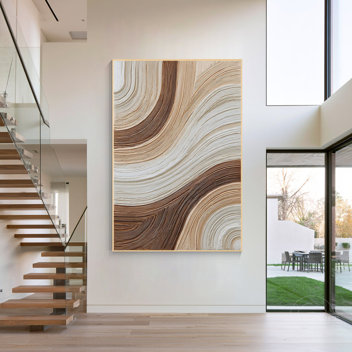 Large framed vertical brown textured painting hanging on a neutral entryway wall with modern interior lighting.