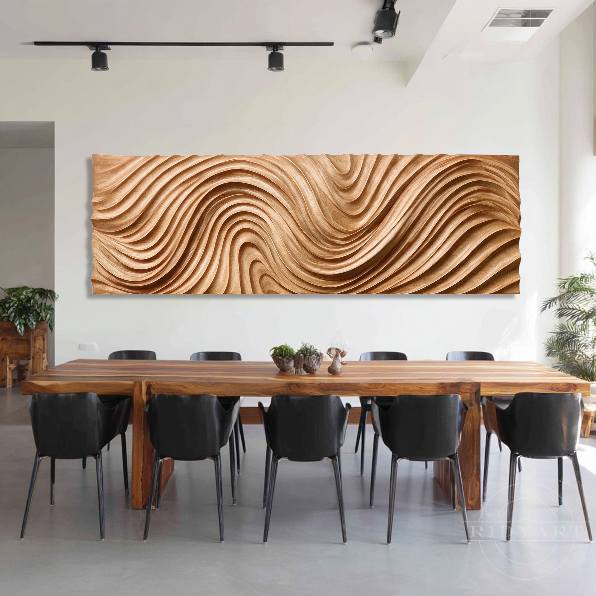 Wooden wave wall art displayed on a white wall above a long wooden dining table and black chairs with track lighting.